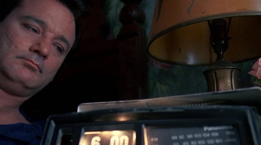A screenshot from the movie Groundhog Day with Bill Murray watching a clock.
